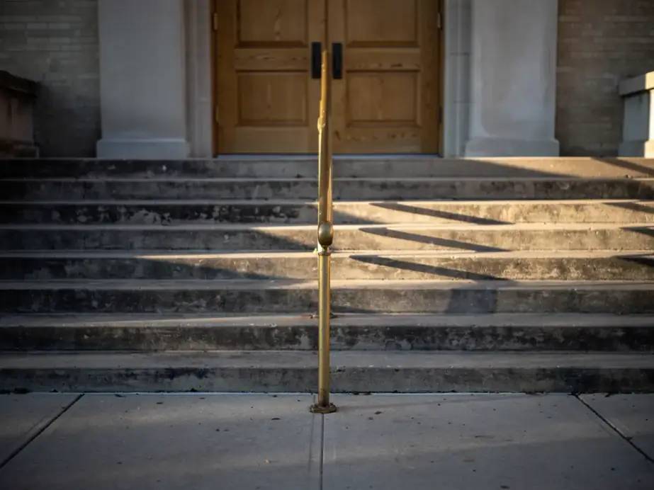 Stone courthouse steps and a brass handrail in early morning light
